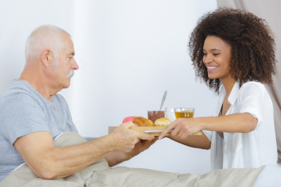 Caregiver handing food tray to elderly