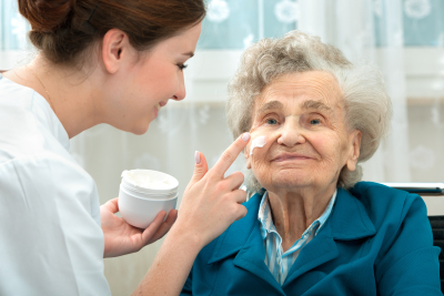 Caregiver applying skin care product on elderly