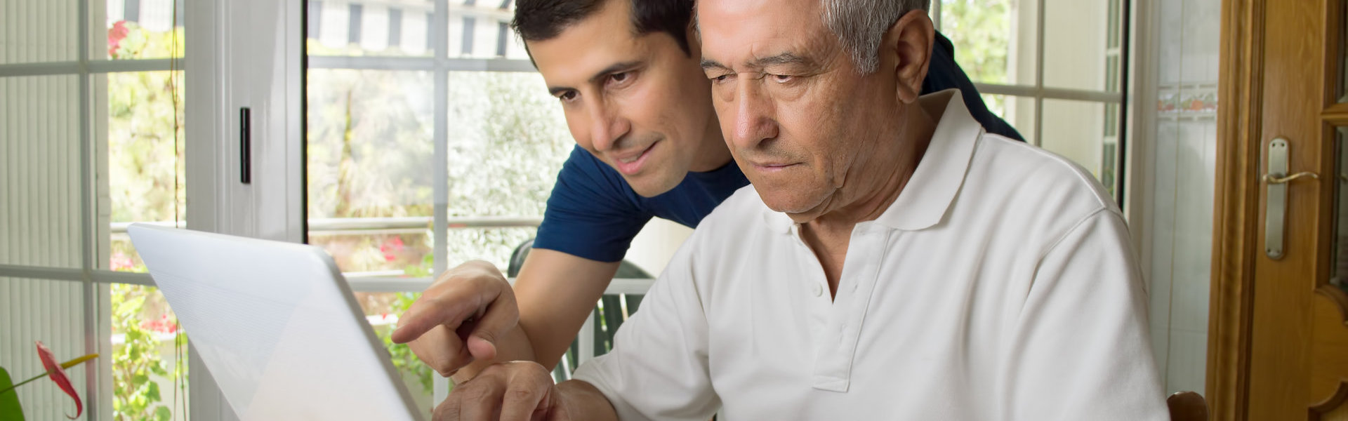 caregiver assisting senior on using laptop